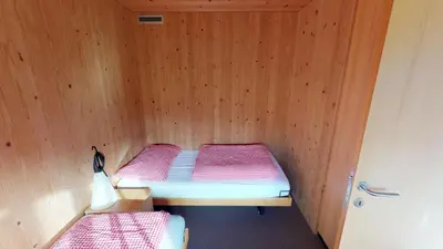 two beds in a room with wooden walls at Reka-Feriendorf Urnäsch in Urnäsch