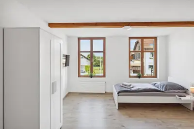 a bedroom with white walls and a bed and windows at FENUS Apartment mit traumhaftem Bergblick SGT02 in Grabs