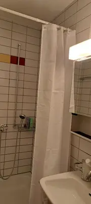 a bathroom with a shower with a white shower curtain at Sonniges 1-Zimmerappartement mit Blick über Kreuzlingen in Kreuzlingen