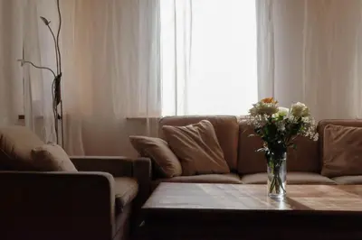 a living room with a couch and a vase of flowers on a table at Ferienwohnung im Grünen in Altstätten