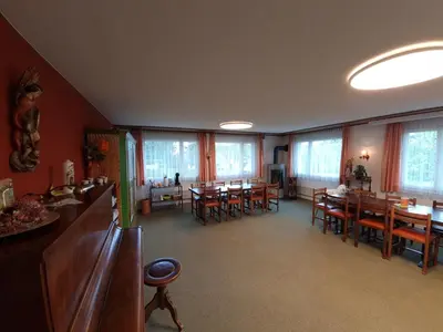 a dining room with tables and chairs and windows at Haus St.Michael in Dozwil