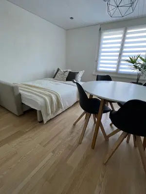 a bedroom with a bed and a table and chairs at Black&White Apartment in Uzwil