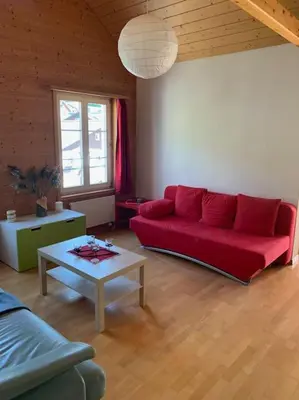 a living room with a red couch and a table at Dachwohnung Zentrum Unterwasser in Unterwasser