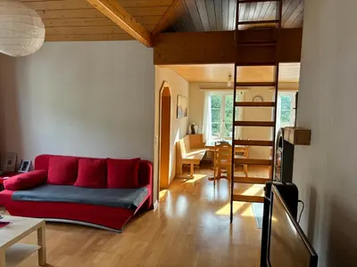 a living room with a red couch and a dining room at Dachwohnung Zentrum Unterwasser in Unterwasser