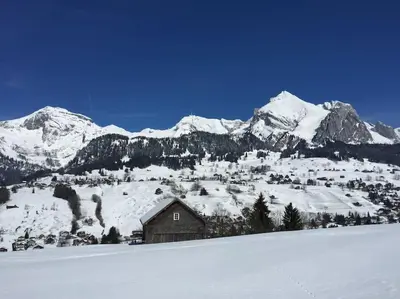 a cabin in the snow with mountains in the background at Dachwohnung Zentrum Unterwasser in Unterwasser