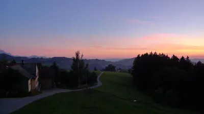 a sunset over a grassy hill with a road at Hirschen Wald - Gasthaus & Bäckerei in Wald