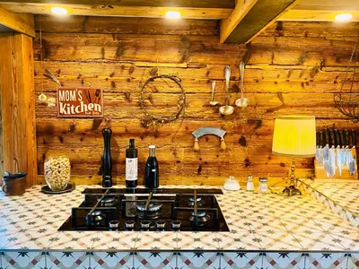 a kitchen with a stove and bottles of wine at Birkenhof, Haus Märli in Herisau