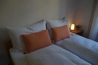 a bed with white pillows and a lamp on a table at Villa Donkey BnB in Degersheim
