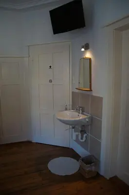 a bathroom with a sink and a mirror and a door at Villa Donkey BnB in Degersheim