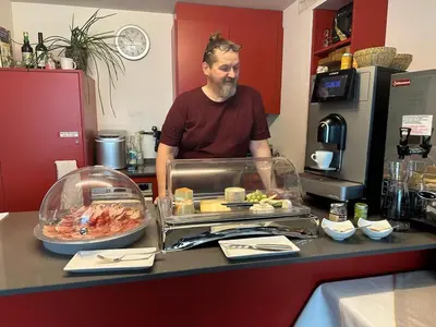 a man standing behind a counter with a buffet of food at Hotel Säntis Teufen in Teufen