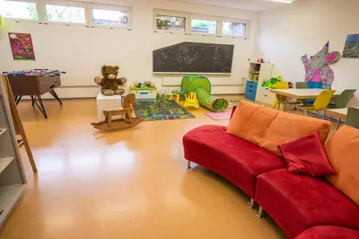 a living room with a red couch and a classroom at Jugendherberge Romanshorn in Romanshorn