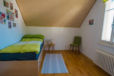 a small bedroom with a bed and a chair at Naturoase Säntisblick-Auszeit am Wald und Bach in Kradolf