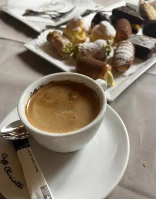 a cup of coffee on a plate next to a plate of pastries at il fiore Hotel Steinach SG in Steinach