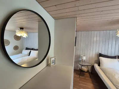 a mirror in a room with two beds and a bed at Villa Donkey Ferienwohnung in Degersheim