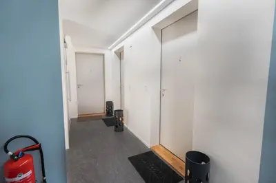 a hallway with white walls and a red suitcase at INN JOY Apartments - Sankt Gallen Center in St. Gallen