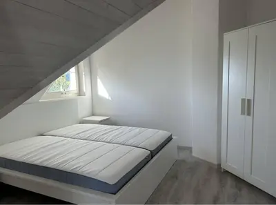 a white bedroom with a bed and a window at Dachwhg an schöner Aussichtslage in Berneck