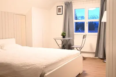 a white bedroom with a bed and a table and a window at Alter Zoll in Teufen