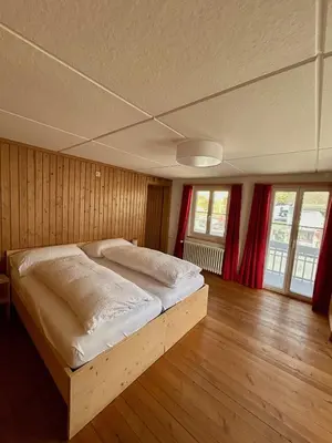 a large bed in a room with wooden floors and windows at Gasthof Ochsen in Nesslau