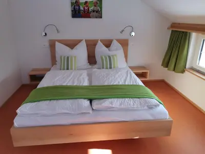 a bedroom with a large bed with green and white pillows at Gästehaus Eisenhut in Walzenhausen