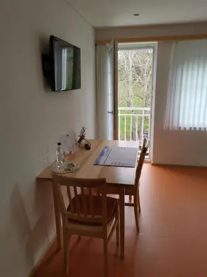 a dining room table with two chairs and a laptop on it at Gästehaus Eisenhut in Walzenhausen