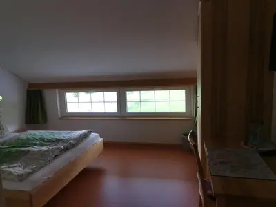 a bedroom with a bed and a desk and a window at Gästehaus Eisenhut in Walzenhausen