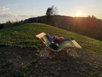 a person laying on a park bench in a field at Gästehaus Eisenhut in Walzenhausen