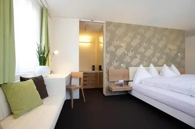 a bedroom with a bed and a desk and a mirror at Anker Hotel Restaurant in Teufen
