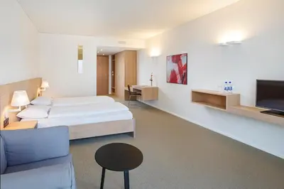 a bedroom with a bed and a couch and a tv at Newstar Hotel (Free Parking) in St. Gallen