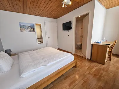 a bedroom with a bed and a desk and a bathroom at Hotel Taverne zur Linde in Bischofszell