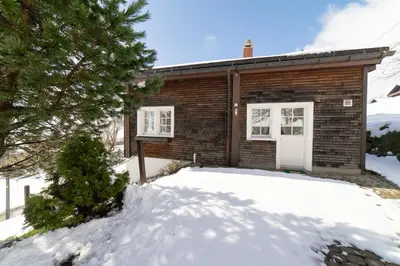 a brick house in the snow with a tree at Nuessli in Wildhaus