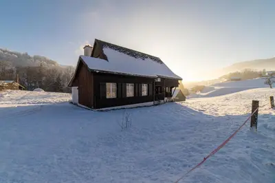 a house covered in snow in a snowy field at Chammern in Nesslau