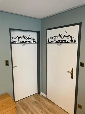 two doors in a room with mountains on the wall at Ferienwohnung Edelweiss in Wolfhalden
