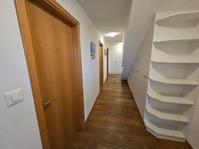 a hallway with white shelves and a wooden door at Private Etage 5 Min vom Bahnhof - Parken - Küche - Netflix in Widnau