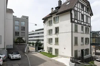 a white and black building with a car parked next to it at INN JOY Apartments - Roter Platz in St. Gallen