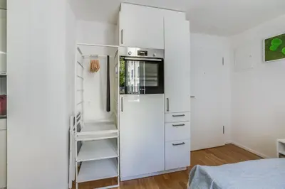 a white refrigerator in a white kitchen with a ladder at HRE Apartments St Gallen City Center in St. Gallen