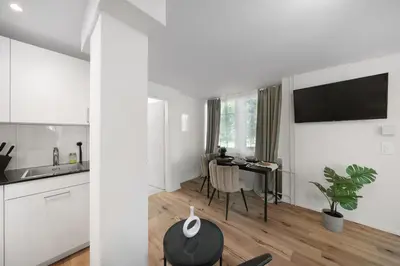 a white kitchen with a table and a dining room at Book2Stay - modernes Studio OLMA-Areal in St. Gallen
