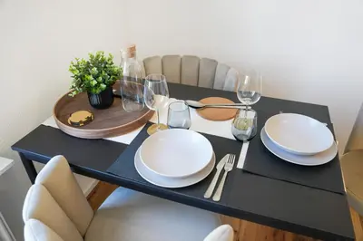 a black table with white plates and wine glasses at book2stay modernes Apartment OLMA-Areal in St. Gallen