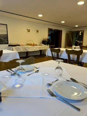 a table with white plates and forks and napkins at Hotel Kaubad in Appenzell