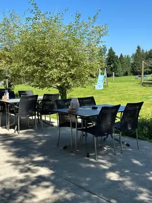 a group of tables and chairs with a field in the background at Hotel Kaubad in Appenzell