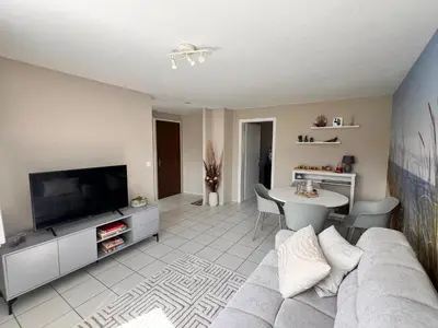 a living room with a couch and a tv and a table at Ferienwohnung SUN SAND SEA in Horn