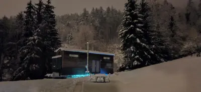 a small cabin in the snow with two chairs in front at Tiny House im Grünen in Sankt Margrethen