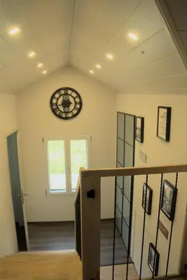 a room with a clock on the wall and a staircase at Chalet Wahida- Wellness Oase im Neckertal! in Sankt Peterzell