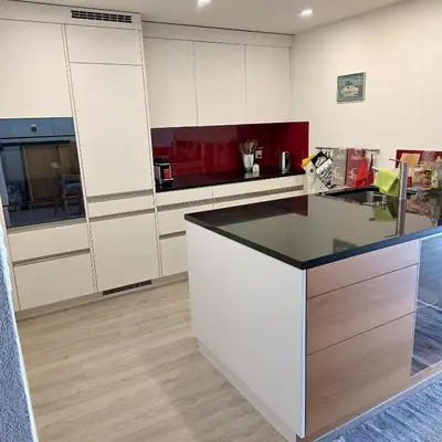 a kitchen with white cabinets and a black counter top at Ferienwohnung Halden in Unterwasser