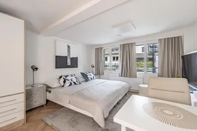 a white bedroom with a bed and a living room at Ferien Studio Wohnung Altstadt Multergasse 20 in St. Gallen