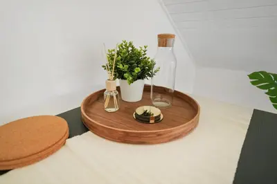 a wooden table with a bottle and flowers on it at book2stay moderne Wohnung OLMA-Areal in St. Gallen