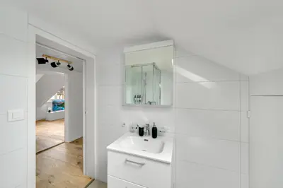 a white bathroom with a sink and a mirror at book2stay moderne Wohnung OLMA-Areal in St. Gallen