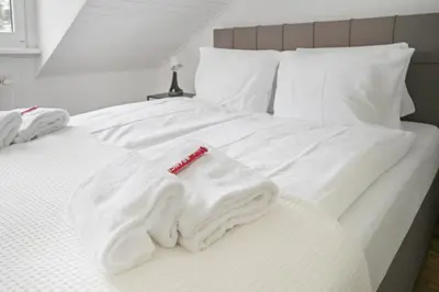 a white bed with towels and a thermometer on it at book2stay moderne Wohnung OLMA-Areal in St. Gallen