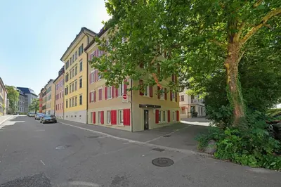 a yellow building with red windows on a city street at book2stay moderne Wohnung OLMA-Areal in St. Gallen