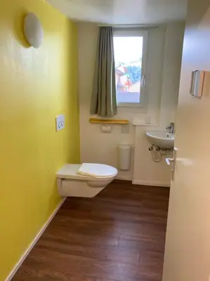 a bathroom with a toilet and a sink and a window at 03 - Gästehaus Erika - Hundwil - Appenzellerland in Hundwil