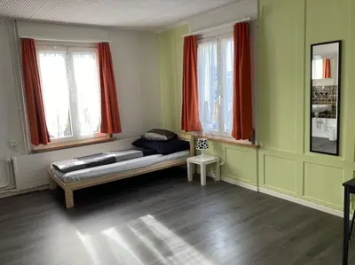 a living room with a couch and two windows at 08 - Gästehaus Erika - Hundwil - Appenzellerland in Hundwil
